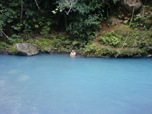 A bather rests on the bank across the Rio Celeste from this property.