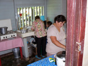 Grandmother, granddaughter, and daughter-in-law work on lunch in the secondary kitchen.