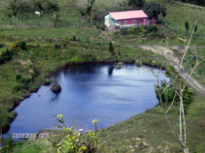 A small lake sits in the valley center with an employee house nearby.  