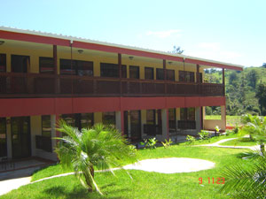 Two 2-story hotel buildings with large rooms frame a sloping central garden. 