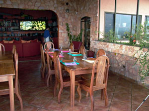 The dining room is srurrounded by huge windows atop a rock wall.