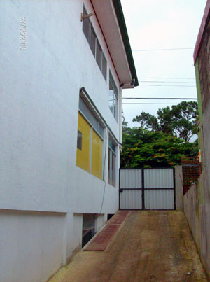 A paved driveway behind the building leads down to the back garden and the first level where the apartments are.