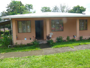 The house is on a wide, quiet residential street with a paved sidewalk. 