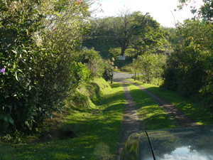 The gated driveway ascends from the paved lake highway.