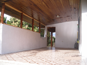 The large carport has a handsome wood ceiling, tile floor, and a doorway leading to th side patio.