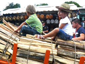 Two children ride atop an oxcart full of lumber to be auctioned off to support the church.