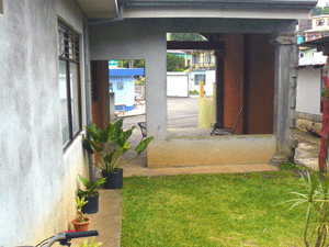 The carport is partially walled from the back lawn and has entrances to the house and the back yard.