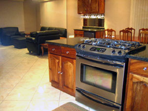 Beyond the fine stove in the center island one can see the living room with its leather furniture and adjacent wetbar.