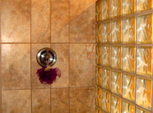 A shower has fine tile and a glass-block wall.