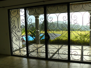 The living room has a large expanse of glass doors and windows protected with attractive wrought-iron security screens. 