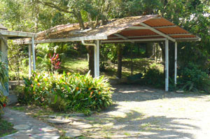 The carport sits between the cottage and the pond and aviary.