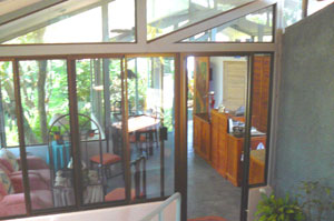 From the unifying center patio, one looks through the kitchen, dining room, and living room windows to the cottage and the front yard of the compound. 