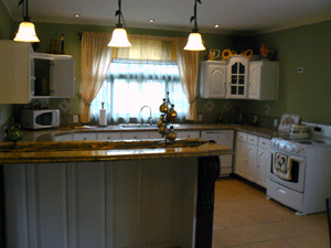 The large-windowed kitchen has a breakfast bar and is open to the dining area.