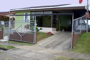 The home has a glassed front porch, a paved driveway, carport, and metal fence and sliding electric driveway gate. 