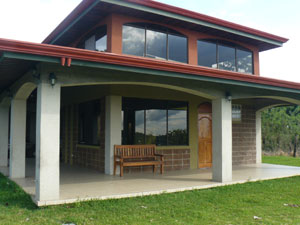 The huskily-built home takes advantage of its hilltop location with a glassy second story and a wide covered veranda on two sides at ground level. 