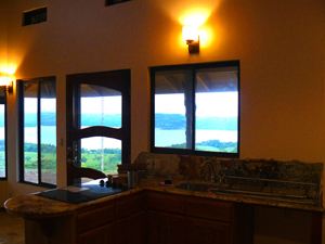 The location of the kitchen in the open plan provides terrific views of the lake and volcano. Lighting fixtures are attractive high-quality elements of the small luxury home.