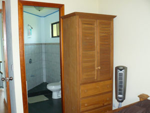 The master bedroom has one of the 3 bathrooms. One wall has built-in wooden closets while an armoire stands against the west wall. 