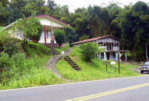 The house sits above the road next to a small commercial building that is also for sale.