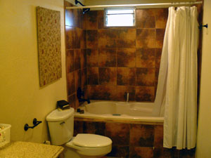 The bathroom has distinctive tile, a  deep tub and a shower.