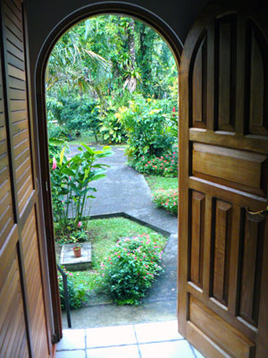 From the handsome front doorway, the scene is of lawn, trees, and ornamentals.