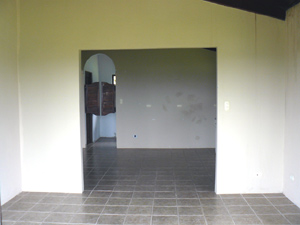 The main entry through wide glass doors from the porch leads to a living room or dining area with the open kitchen beyond.