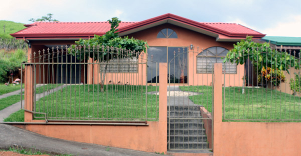 The 3BR 2BA modern home has a nice green lawn behind its ornamental iron fence.