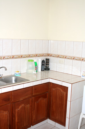 The bright kitchen has a high ceiling and custom hardwood cabinets beneath its tile countertops.