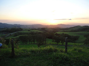 The sun sets behind the distance coastal mountains rendering beautiful the foothills, the Tempisque River Basin and the Gulf of Nicoya.