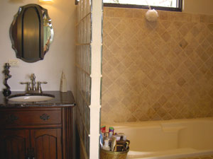 The attractive bathroom has travertine tile and an extra-large bathtub.