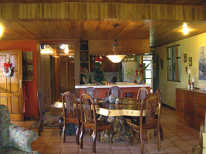 Beyond the dining area with its beautful free-form table and custom chairs is the pass-through to the outer kitchen/bar  with the large new main kitchen beyond that.  