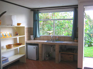 The kitchenette has a wide tile counter and a sink as well as a small refrigerator. 