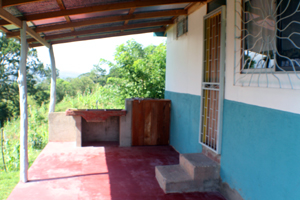 The patio at rear of house looks over a valley with stream and surrounding hills.